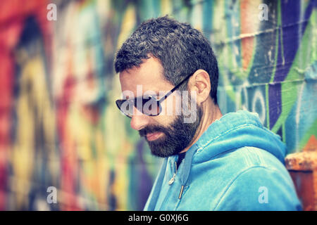 Closeup Portrait von gut aussehender Mann mit stilvollen Bart und Sonnenbrille, über bunte Stadt Wand Hintergrund stehen Stockfoto