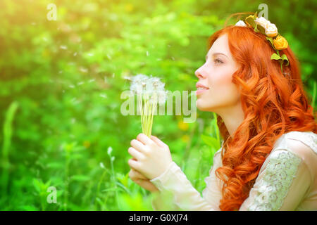 Porträt eines schönen Mädchens tragen Blumenkranz, genießen Frühling Wiese hält in Händen Blumenstrauß ein Löwenzahn Stockfoto