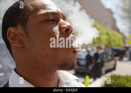 Afroamerikanischen jungen Mann bläst Dampf - USA Stockfoto