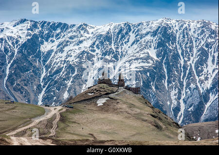 Georgien. Stepantsminda Dorf. Dem Sameba orthodoxe Kirche auf dem Hintergrund einer Bergquelle. Stockfoto