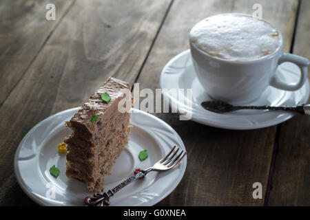 Schokoladenkuchen auf den weißen Teller mit einer Tasse Kaffee Stockfoto