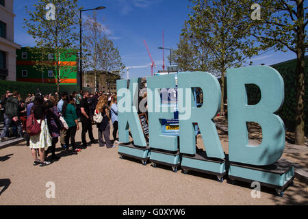 Eine lange Schlange von Menschen, die neben einem großen Schild für Lebensmittel auf ein beliebtes Londoner Straße Lebensmittelmarkt bekannt als The Kerb Schlange. Stockfoto