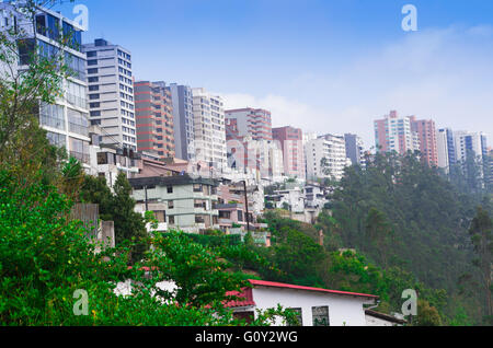 Quito-Skyline aus Tal mit Mehrfamilienhäusern sitzen am Rand des grünen Gebirgshintergrund Seiten- und blauen Himmel gesehen Stockfoto