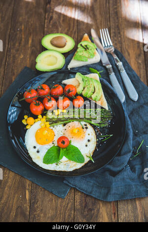 Spiegeleier, Cherry-Tomaten, Avocado, Spargel und Toast Frühstück Stockfoto