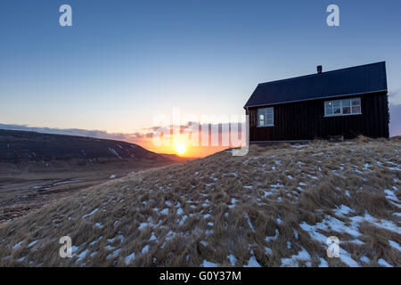 Sonnenuntergang von einem schwarzen isländischen Häuschen in Westisland Stockfoto
