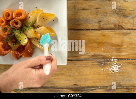 Zarte Frauenhand Verglasung Scheiben von Lachs und starry Stör Fisch, Ukraine Stockfoto