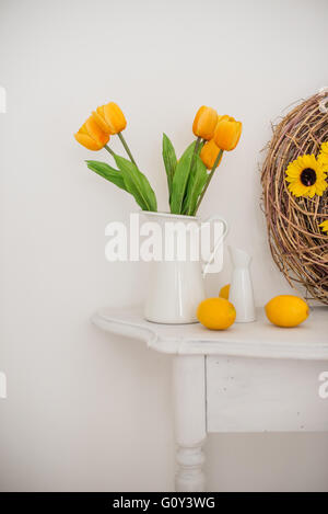 Tulpe Blumen in einem Krug mit Zitronen auf weißen Tisch Stockfoto