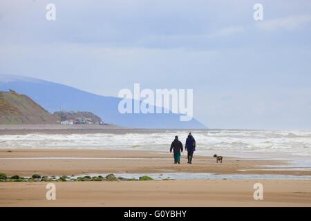 Saint Bienen. Paar, Hund am Strand spazieren gehen. Cumbria, England, Vereinigtes Königreich, Europa. Stockfoto