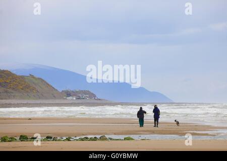 Saint Bienen. Paar, Hund am Strand spazieren gehen. Cumbria, England, Vereinigtes Königreich, Europa. Stockfoto