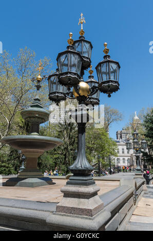 Blick auf kunstvolle Kandelaber und Wasser-Brunnen in City Hall Park, New York, mit dem Rathaus im Hintergrund. Stockfoto