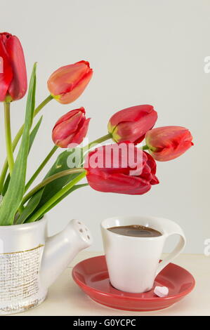 Rote Tulpen mit einer Tasse Kaffee auf einem Holztisch Stockfoto