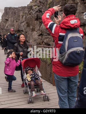 Süd-West Island, Island. 4. August 2015. Ein Tourist Vater nimmt ein Familienfoto auf der Brücke Weg zwischen Mauern aus vulkanischem Gestein durch berühmte Almannagja Canyon im Thingvellir National Park, ein Grabenbruch markieren das Wappen des Mittelatlantischen Rückens zwischen den nordamerikanischen und eurasischen Platten, es ist eine visuelle Darstellung der Kontinentalverschiebung, die zwischen zwei tektonischen Platten gebildet. Es ist eine der meistbesuchten Touristenattraktionen in Island, wo Tourismus ein wachsender Sektor der Wirtschaft geworden. © Arnold Drapkin/ZUMA Draht/Alamy Live-Nachrichten Stockfoto