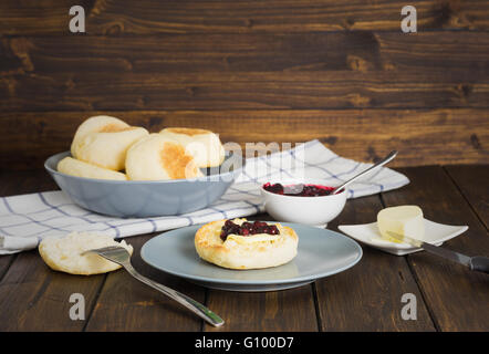 Englische Muffins mit Marmelade und Butter auf hölzernen Hintergrund im rustikalen Stil Stockfoto