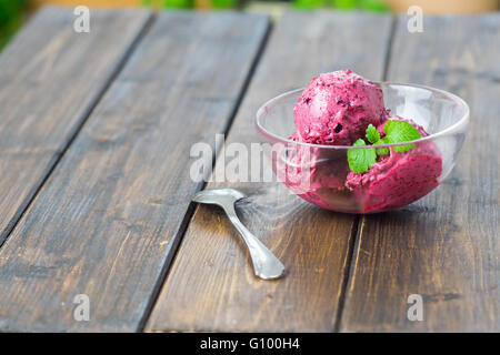 Hausgemachte Heidelbeer-Eis oder Sorbet serviert in einer Glasschale auf Holztisch im rustikalen Stil Stockfoto