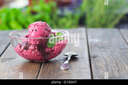 Hausgemachte Heidelbeer-Eis oder Sorbet serviert in einer Glasschale auf Holztisch im rustikalen Stil Stockfoto