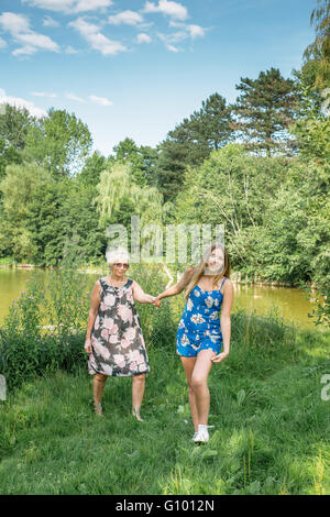 Mädchen zieht die Frau ihre Hand. Mutter und Tochter gehen. Großmutter und Enkelin. Stockfoto