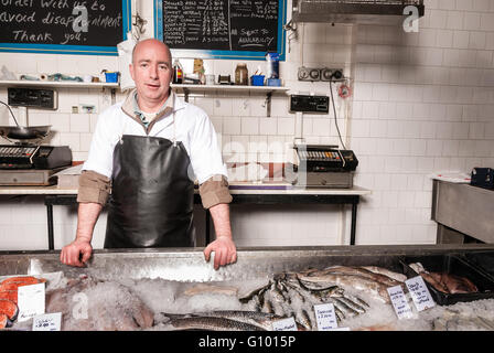 Fischhändler Posen hinter seiner Theke, UK Stockfoto