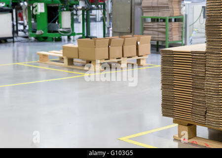 Das Innere der Montagehalle mit einem ausgewiesenen Kommunikationszone und Pappe auf Holzpaletten gelagert. Stockfoto
