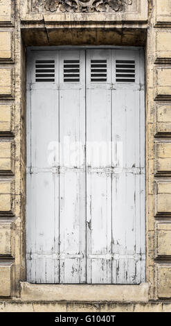 Verwitterte weiße Holzfenster Panel mit einem rostigen Metall Scharniere und mit Farbe weiß Abplatzungen, gechipt und peeling texturiert. Stockfoto