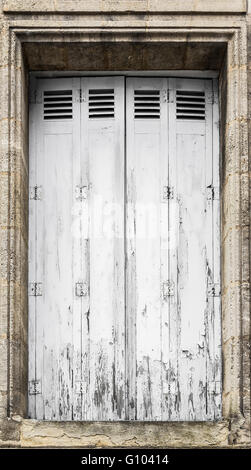 Verwitterte weiße Holzfenster Panel mit einem rostigen Metall Scharniere und mit Farbe weiß Abplatzungen, gechipt und peeling texturiert. Stockfoto