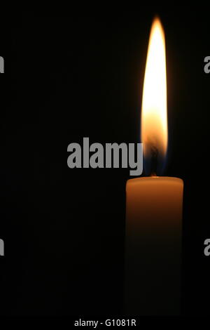 Einzelne Kerzenflamme vor einem schwarzen Hintergrund in einer Kirche Stockfoto