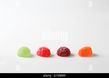 vier Fruchtgummi-Bonbons mit Zucker auf weißem Hintergrund beschichtet Stockfoto