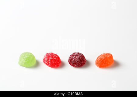 vier Fruchtgummi-Bonbons mit Zucker auf weißem Hintergrund beschichtet Stockfoto