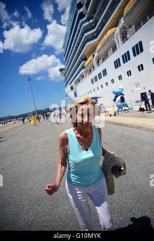 Reife Frau tanzt mit Musik am Eingang Kreuzfahrt im Hafen von Corfu, Griechenland Stockfoto