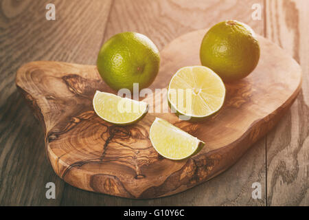 Reife Limetten Olivenöl Board über Eichentisch Stockfoto