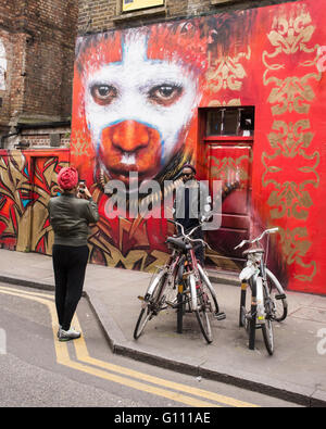 Schwarze Afro Hipster mit Sonnenbrille eine Aufnahme vor einer Wand mit einer großen Graffiti repräsentieren einen Aborigine-Mann Stockfoto