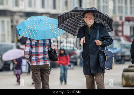 Aberystwyth Wales UK, Samstag 07 Mai 2016 UK Wetter: wie viel von England am heißesten Tag des Jahres so weit swelters, erlebt viel des Westens und Wales einem nassen und regnerischen Tag. Met Office gelbe Warnung ist für die gesamte Wales für den Rest des Tages, mit der Möglichkeit der lokalisierten Starkregen.   Im Bild: Menschen auf der feuchten Promenade in Aberystwyth bergende unter ihren Regenschirmen Photo Credit: Keith Morris / Alamy Live News Stockfoto