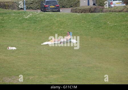 Portsmouth, UK. 7. Mai 2016. Ein Mann sonnt sich mit seinem Hund auf eine kultige Liegestuhl. Bildnachweis: Marc Ward/Alamy Live-Nachrichten Stockfoto