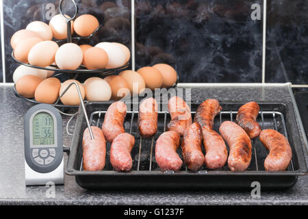 Überprüfen die Gartemperatur von gegrillten Würstchen mit ein digitales Fleischthermometer Stockfoto