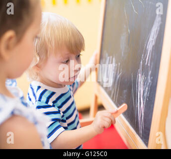 Kleine Kinder mit Kreide in der Nähe von Blackboard-Seitenansicht Stockfoto