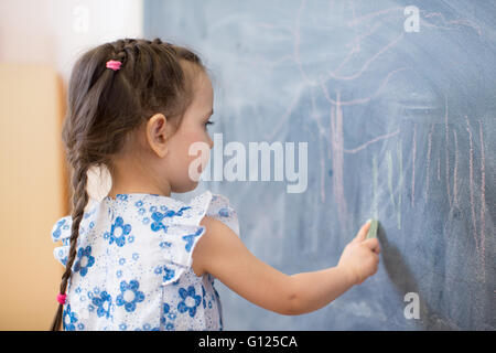 kleines Mädchen Seitenansicht in der Nähe von blackboard Stockfoto