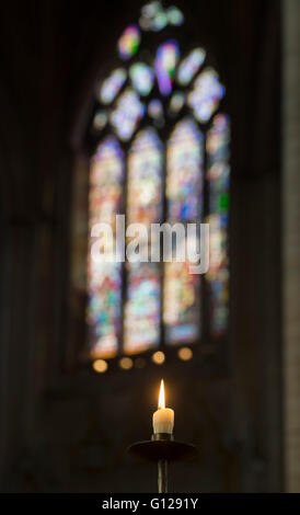 Einzelne Leuchten Gebet Kerze vor eine moderne Glasfenster in Ely, selectve konzentrieren. Cambridgeshire, England Stockfoto