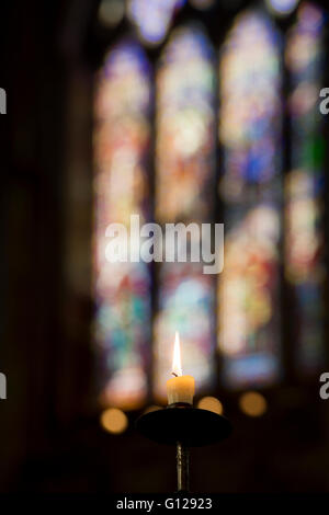 Einzelne Leuchten Gebet Kerze vor eine moderne Glasfenster in Ely, selectve konzentrieren. Cambridgeshire, England Stockfoto