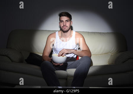 Nahaufnahme, schönen jungen Mann Essen Popcorn auf der Couch. Indoor. Stockfoto