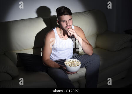 Nahaufnahme, schönen jungen Mann Essen Popcorn auf der Couch. Indoor. Stockfoto