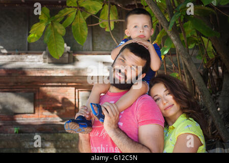 Gesicht Portrait schöne Familie - glückliche Mutter, Vater, die Schultern Spaziergang mit lustigen Baby Sohn festhalten. Stockfoto