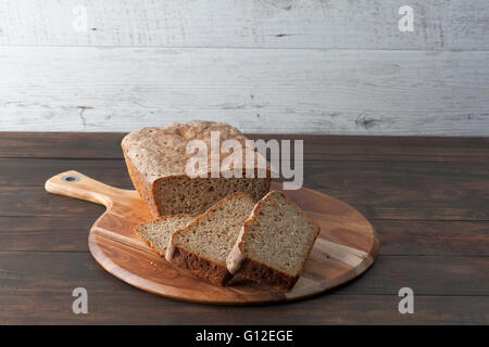 Hausgemachte dunkle Roggen Surdough Laib Brot und in Scheiben geschnitten auf Runde Schneidebrett. Horizontales Bild mit Textfreiraum. Stockfoto