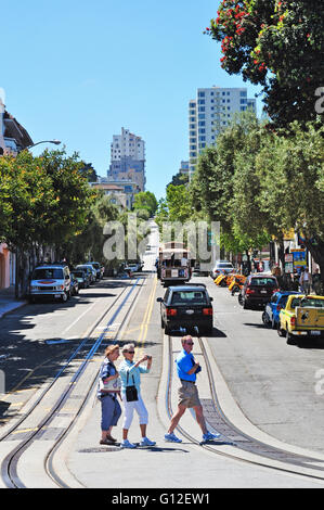 San Francisco, Kalifornien, USA: Menschen und eine Seilbahn auf Schienen im Hyde Street in der Fisherman's Wharf Nachbarschaft Stockfoto