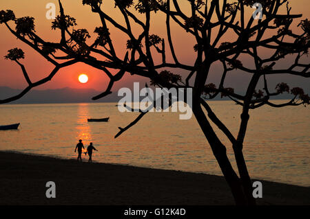 Zwei Menschen, die zu Fuß am Ufer des Lake Malawi bei Sonnenuntergang, Cape Maclear Stockfoto