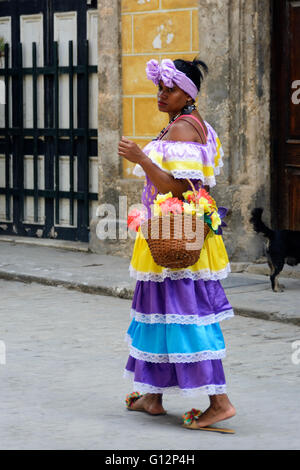 Eine Blumenverkäuferin tragen Tracht Spaziergänge entlang der Straße in Alt-Havanna, Havanna, Kuba Stockfoto