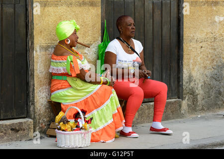 Ein kubanische Puppe Verkäufer tragen Tracht und raucht eine Zigarre entspannt mit einem Begleiter in Alt-Havanna, Havanna, Kuba Stockfoto