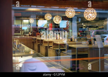 Innenraum von Yo! Sushi durch das Fenster der Baker Street, London, mit moderner Beleuchtung und leeren Sitzgelegenheiten. Stockfoto