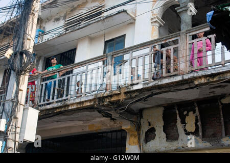In Armut lebenden Menschen sind auf dem Balkon einer alten heruntergekommenen kolonialen Ära Gebäude in Kampong Cham, Kambodscha umhergehen. Stockfoto