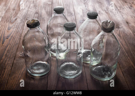 Draufsicht der schmutzige leere Vintage transparenten Glasflaschen mit Stopper auf Holzdeck Hintergrund Stockfoto