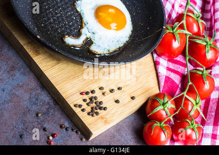 Frühstück mit Spiegelei, Cherry-Tomaten und Gewürzen auf rustikalen Küchentisch Stockfoto