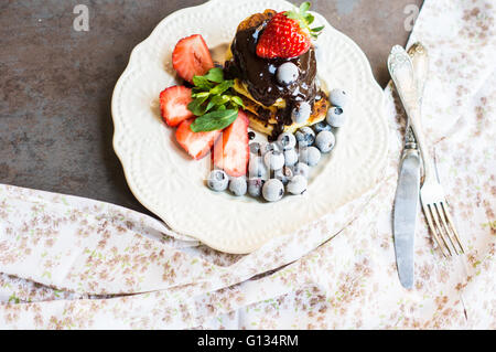 Käse-Pfannkuchen mit frischen Erdbeeren und Heidelbeeren Früchten und Schokolade zum Frühstück Stockfoto